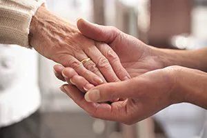 Hands held in a reassuring home-care moment