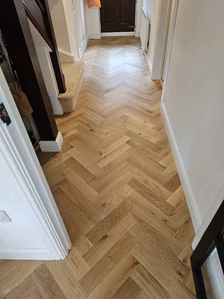 Herringbone wood flooring continuing through a hallway