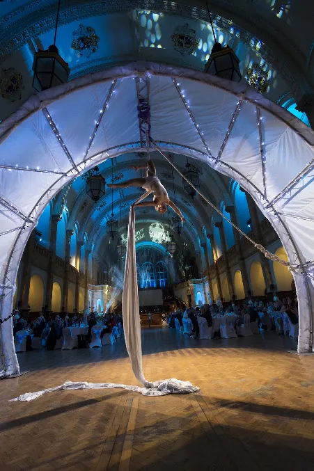 An aerial performance staged beneath an illuminated arch