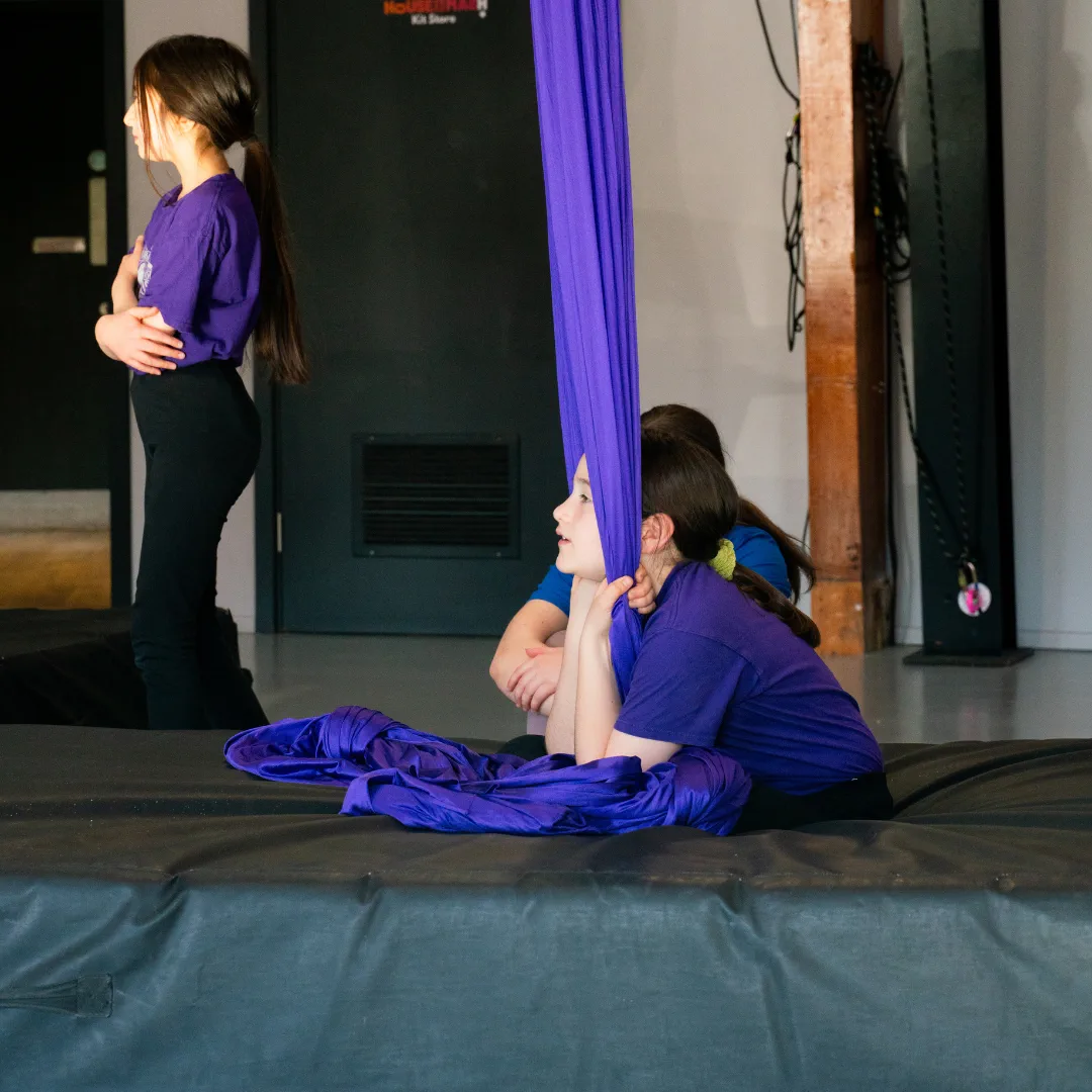Young CircusMASH participants resting on crash mats during an aerial class