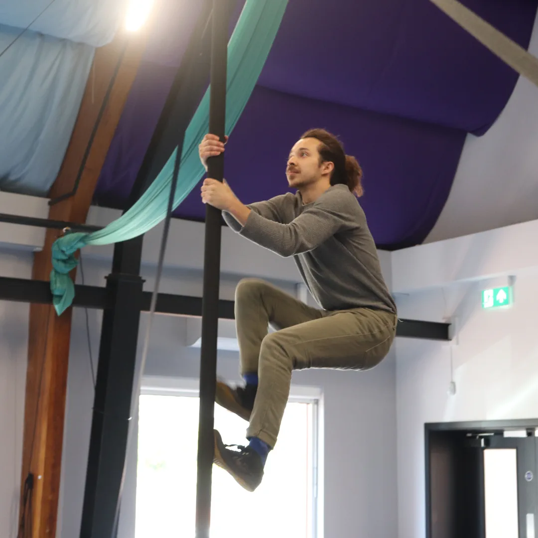 An adult CircusMASH participant climbing a Chinese pole