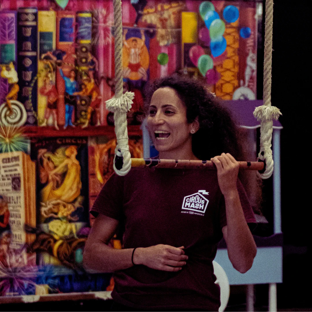 A CircusMASH coach smiling beside a trapeze