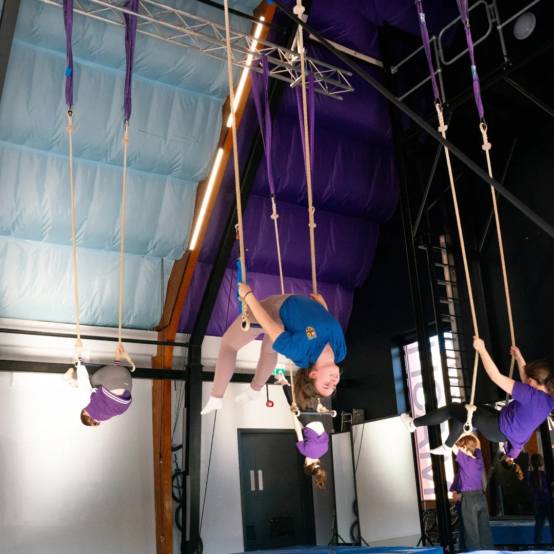 Young CircusMASH participants practising on trapezes during a class