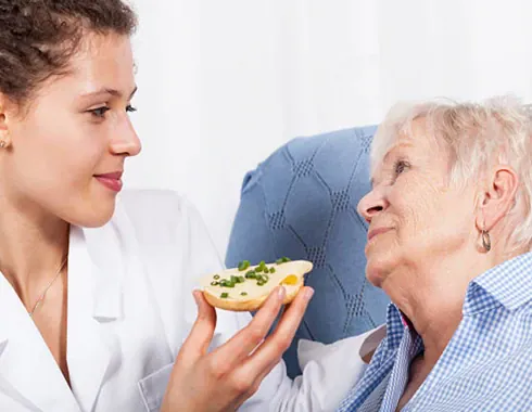 A care worker helping an older client with a meal