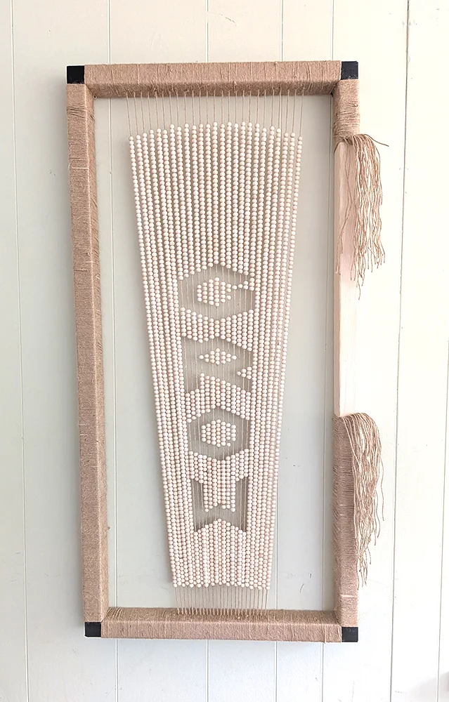 David Osbaldestin’s framed GROW MORE artwork, with pale lettering on a ribbed surface.